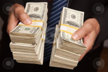 cutcaster-photo-100651424-Businessman-Handing-Over-Stacks-of-Money